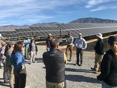 Group of people in discussion beside a Nevada solar array.